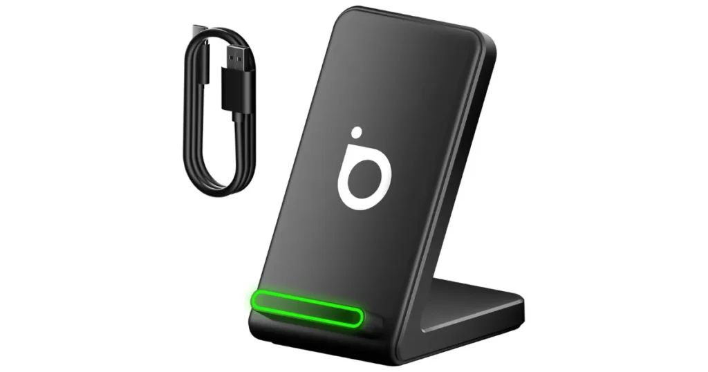 Carregador sem fio vertical (stand) da marca Basike na cor preta. O aparelho tem um LED indicador verde aceso na base, o logo da marca ao centro, e o cabo de alimentação USB é exibido ao seu lado.