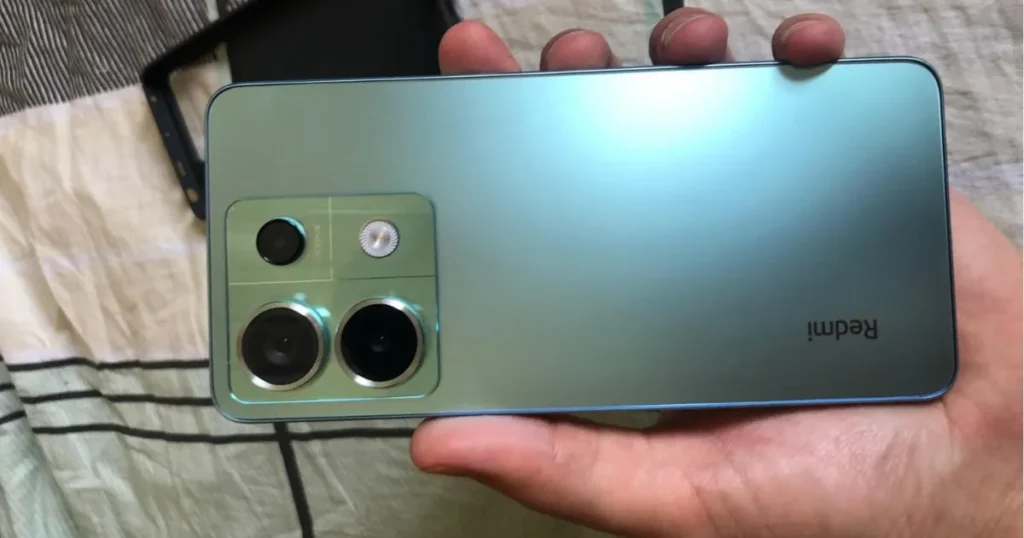 Pessoa segurando um smartphone Xiaomi Redmi Note 13 Pro 5G azul na horizontal, exibindo a parte traseira do aparelho com o módulo de câmeras.
